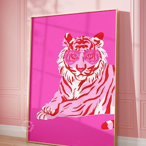 May include: A framed art print depicting a tiger in pink and red hues, sporting pink sunglasses. The tiger is set against a bright pink backdrop, within a gold-coloured frame. The artwork is in a pop art style.