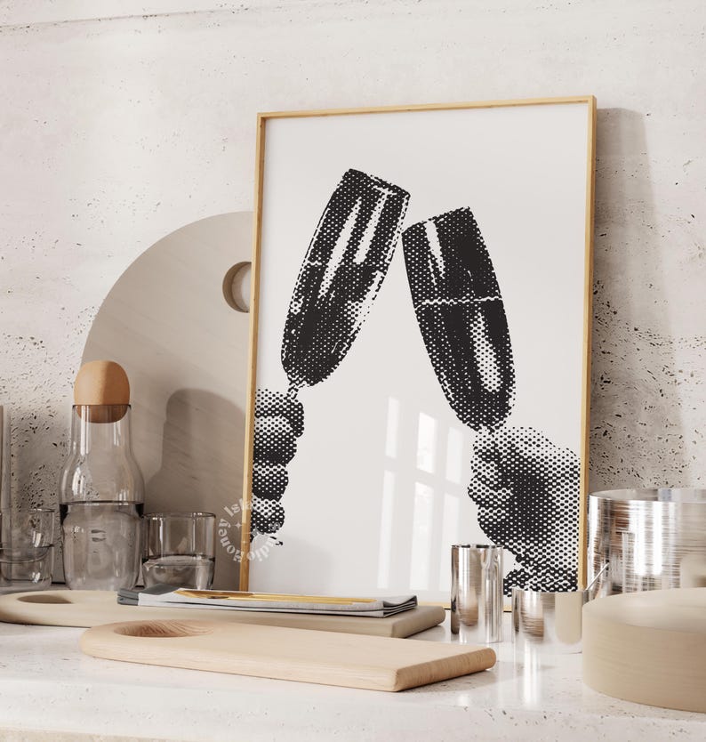 May include: Black and white print of two hands holding champagne glasses up in a toast. The print is framed in a light wood frame.