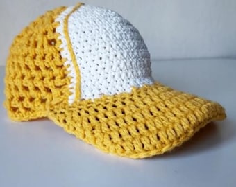 Può includere: Un cappello da baseball all'uncinetto con visiera gialla e corona bianca. Il cappello è realizzato con un punto a rete.