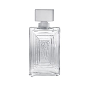 May include: A clear glass bottle with a frosted glass stopper. The bottle has a rectangular shape with a raised design of two figures embracing. The bottle is empty.