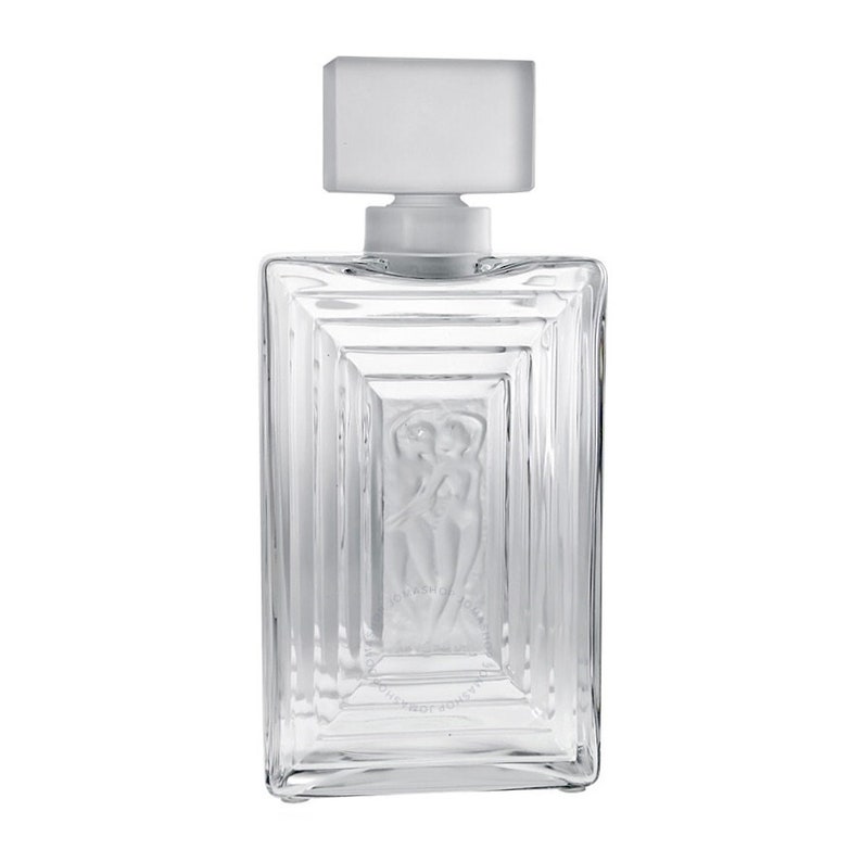 May include: A clear glass bottle with a frosted glass stopper. The bottle has a rectangular shape with a raised design of two figures embracing. The bottle is empty.