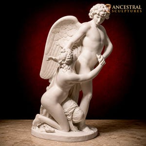 Può includere: Una scultura in stile marmo bianco che raffigura due figure, una in piedi con grandi ali e una in ginocchio, con il testo ANCESTRAL SCULPTURES visibile nell'angolo in alto a destra. Le figure sono intrecciate in una posa classica su una base.