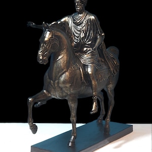 Op de afbeelding: Een bronzen beeld van een man te paard. De man draagt een toga en heeft een baard. Het paard steigert op zijn achterpoten. Het beeld staat op een zwarte sokkel.