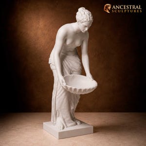 May include: A white sculpture of a figure with hair in an updo, wearing draped fabric around the lower body, standing on a rectangular base and holding a shallow, scalloped bowl. The text ANCESTRAL SCULPTURES appears in the top right corner.