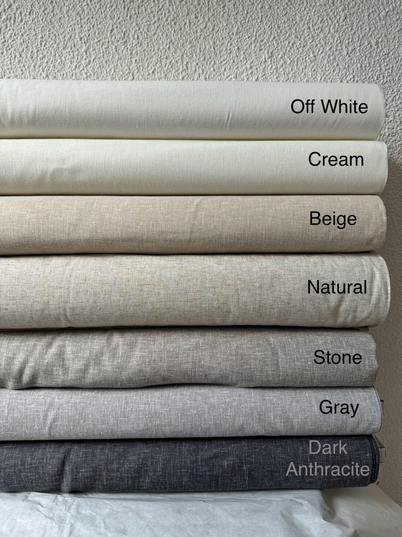 May include: A stack of fabric swatches in various shades of beige, gray, and white. The swatches are labeled with the following names: Off White, Cream, Beige, Natural, Stone, Gray, and Dark Anthracite.