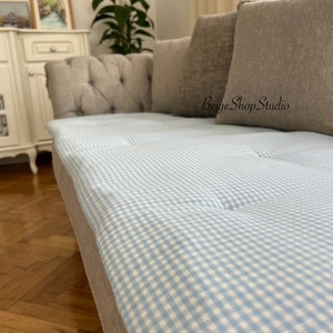 May include: A light blue and white gingham patterned sofa cushion with a beige sofa in the background. The text "BeigeShopStudio" is visible in the image.