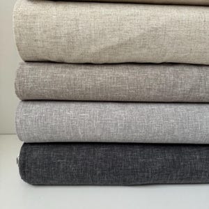 May include: Five rolls of fabric in different shades of gray, from light to dark. The fabric has a subtle texture.
