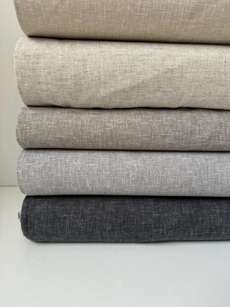 May include: Five rolls of fabric in different shades of gray, from light to dark. The fabric has a subtle texture.