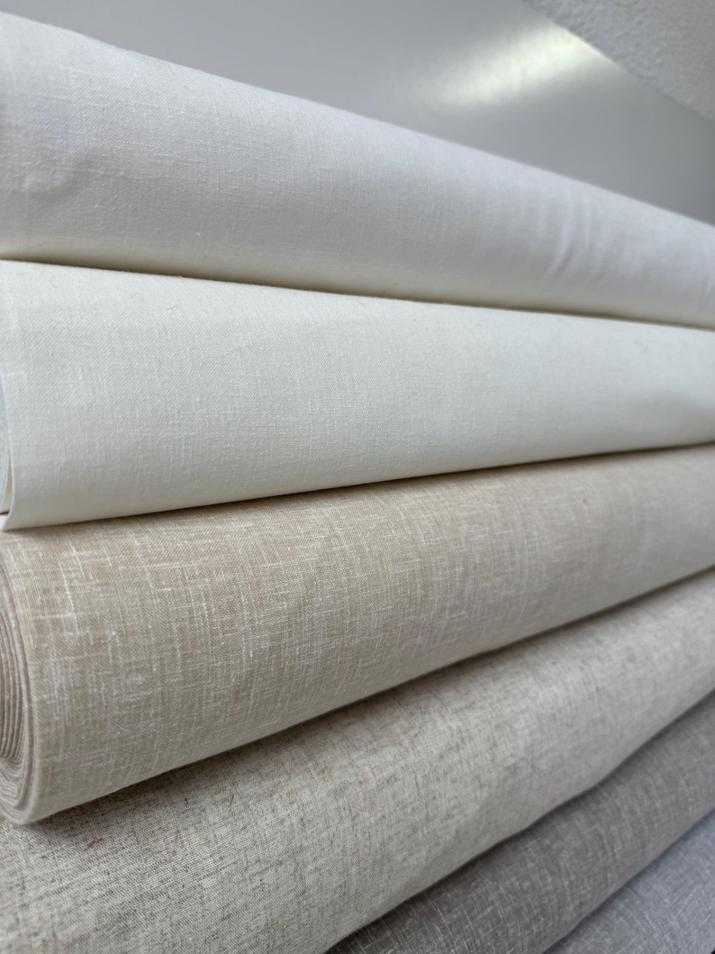 May include: Five rolls of fabric in various shades of beige and white. The fabric is a linen blend and has a subtle texture.