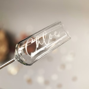 May include: A clear glass champagne flute with the name "Chloe" etched on the side.