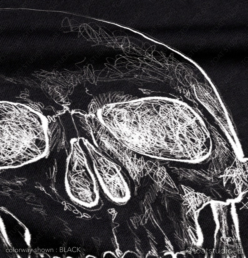 Pode incluir: Tecido preto com um desenho de caveira branca rabiscada. As caracter&iacute;sticas da caveira, incluindo as &oacute;rbitas e a cavidade nasal, s&atilde;o delineadas com uma est&eacute;tica esbo&ccedil;ada e desenhada &agrave; m&atilde;o. O texto "colorway shown: BLACK" est&aacute; na parte inferior.
