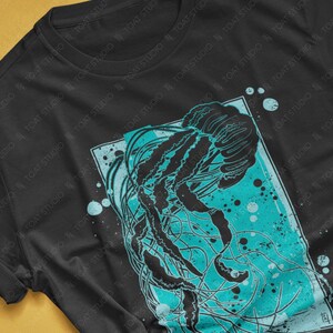 May include: Black t-shirt with a graphic print of a jellyfish in a turquoise and black color scheme. The jellyfish is surrounded by a blue and white background with a white border.