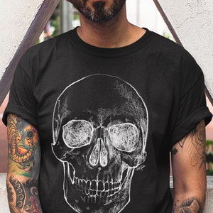 Pode incluir: Camiseta preta com um gr&aacute;fico de caveira branca detalhada. O design da caveira tem um estilo art&iacute;stico rabiscado. O texto "colorway shown: BLACK" est&aacute; na parte inferior esquerda. O logotipo @toatstudio est&aacute; na parte inferior direita.