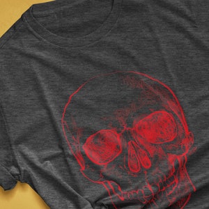Pode incluir: T-shirt cinza escuro mesclado com um design de caveira vermelha. O gr&aacute;fico &eacute; uma representa&ccedil;&atilde;o art&iacute;stica e detalhada de uma caveira. O texto "colorway shown: DARK GREY HEATHER" &eacute; vis&iacute;vel na parte inferior da imagem.
