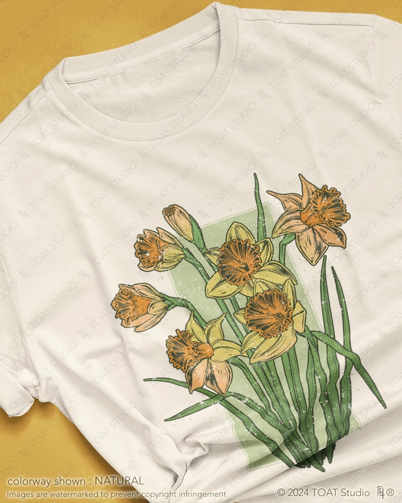 May include: A white t-shirt with a vintage-style illustration of a bouquet of yellow daffodils with green leaves. The design has a distressed, faded look.