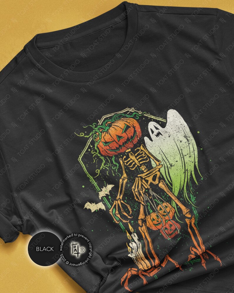 May include: Black t-shirt featuring a Halloween-themed graphic. The design includes a skeleton with a pumpkin head, a ghost, and bats. The color palette consists of orange, green, and white against a black background. The shirt is a crew neck.
