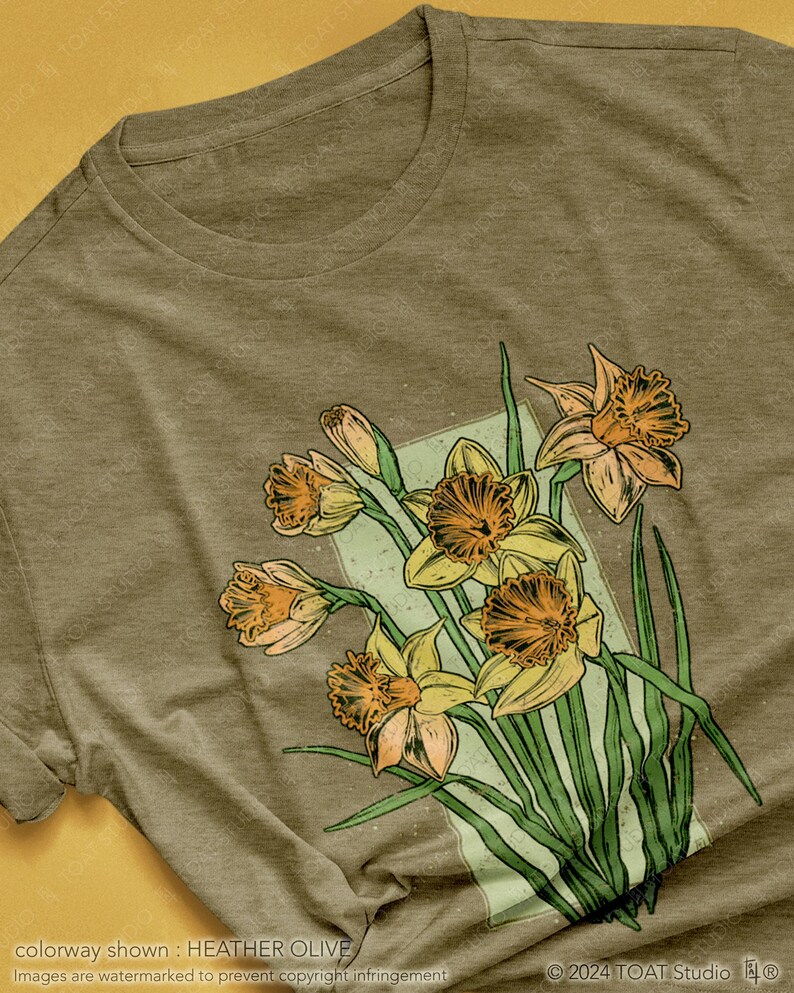 May include: A heather olive t-shirt with a vintage-style illustration of a bouquet of yellow daffodils with green leaves.