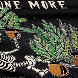 May include: Black graphic tee with the text "ONE MORE" above a skeleton holding potted plants. The skeleton is white, and the plants are green with brown pots. The text "colorway shown: BLACK" is at the bottom.
