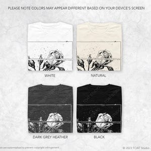 May include: Four t-shirts in white, natural, dark grey heather, and black, each featuring a floral design. The design includes a detailed rose illustration with the text "TOAT STUDIO" and "PLEASE NOTE COLORS MAY APPEAR DIFFERENT BASED ON YOUR DEVICE'S SCREEN".