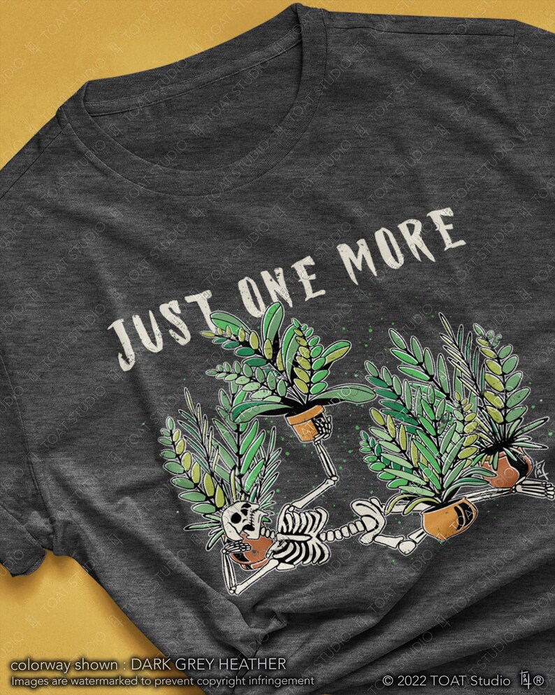 May include: Dark grey heather t-shirt with the text "JUST ONE MORE" above a graphic of skeletons holding potted plants. The skeletons are surrounded by green plants and brown pots. The shirt's colorway is dark grey heather.