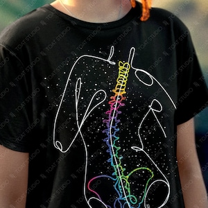 May include: Black t-shirt featuring a white line drawing of a human torso with a colorful spine. The design includes a starry background. The text "colorway shown: BLACK" is at the bottom.