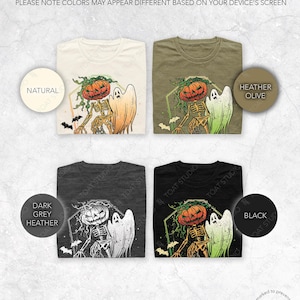 May include: Four folded t-shirts in natural, heather olive, dark grey heather, and black. Each shirt features a Halloween design with a pumpkin-headed skeleton and a ghost. The text "PLEASE NOTE COLORS MAY APPEAR DIFFERENT BASED ON YOUR DEVICE'S SCREEN" is at the top.