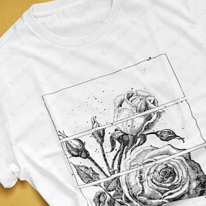 May include: White t-shirt featuring a detailed black and white rose illustration. The design includes a large open rose, buds, and leaves, set within a rectangular frame. The shirt's colorway is white.