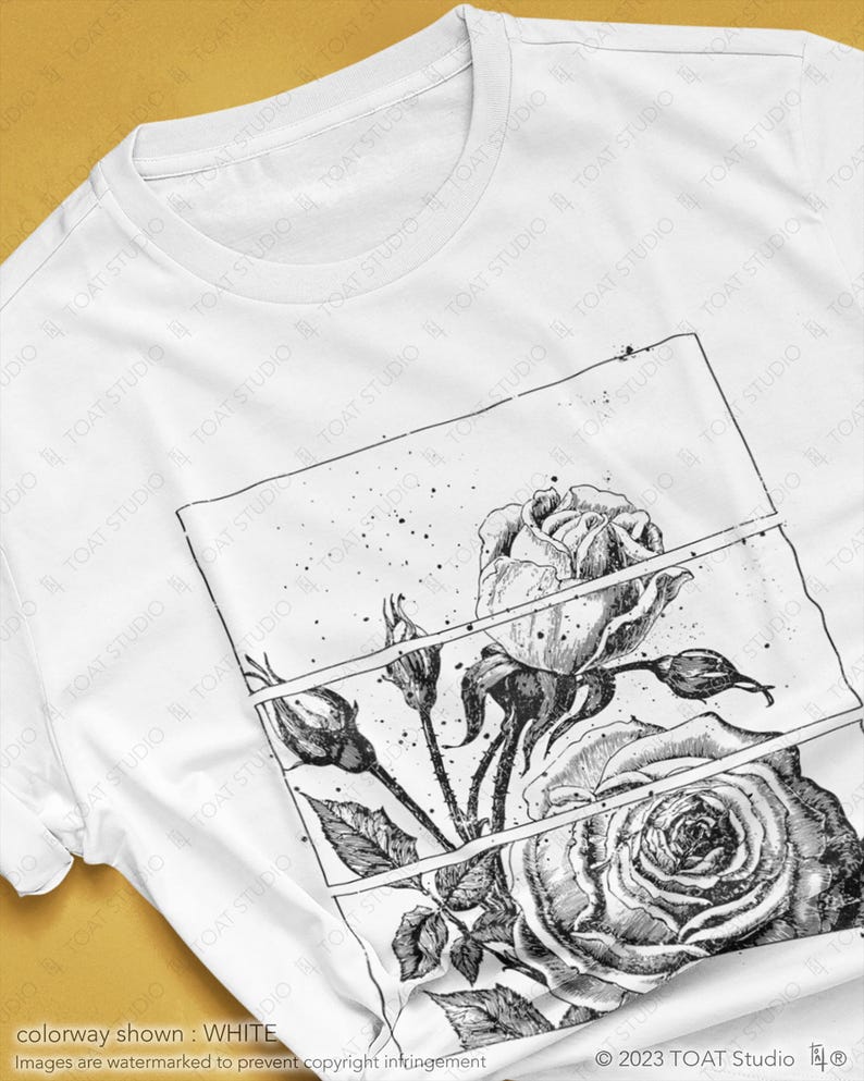 May include: White t-shirt featuring a detailed black and white rose illustration. The design includes a large open rose, buds, and leaves, set within a rectangular frame. The shirt's colorway is white.