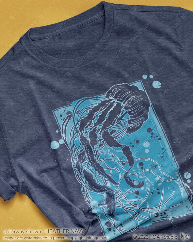 May include: A heather navy blue t-shirt with a graphic print of a jellyfish in blue and white. The jellyfish is surrounded by blue and white dots.