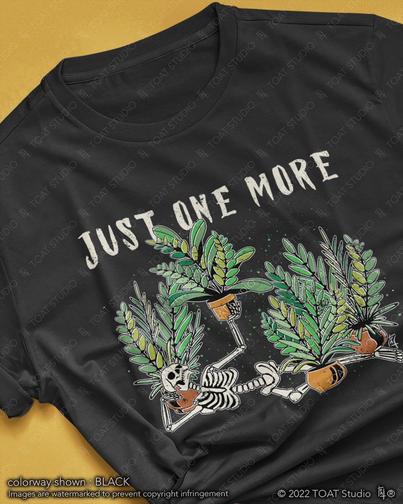 May include: Black t-shirt with a graphic featuring a skeleton reclining with potted plants, and the text "JUST ONE MORE". The design includes green foliage and brown pots. The shirt's colorway is black.