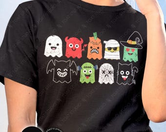 May include: Black t-shirt featuring a colorful Halloween-themed graphic. The design includes various cartoon ghosts and monsters in different colors and expressions. The shirt has a round neckline and short sleeves. The word "BLACK" is printed on a black circle.