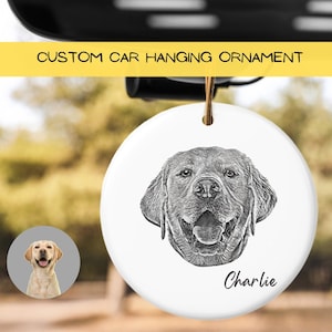 May include: White ceramic car hanging ornament with a black and white drawing of a dog's head. The dog is smiling with its tongue out. The name "Charlie" is written below the dog's head.
