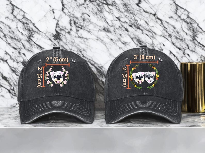 May include: Two black denim baseball caps with embroidered dog faces. The cap on the left has one dog face, and the cap on the right has two dog faces. The caps are 2 inches (5 cm) wide and 3 inches (8 cm) wide.