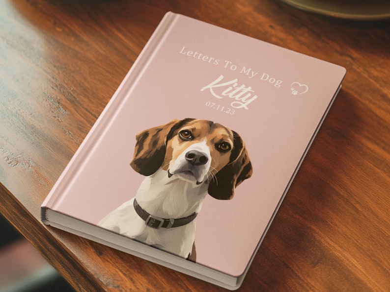 Pode incluir: Um di&aacute;rio rosa intitulado "Letters To My Dog" com um retrato de um c&atilde;o chamado Kitty. O c&atilde;o &eacute; um beagle com pelo castanho e branco, usando uma coleira preta. A data 07.11.23 est&aacute; impressa abaixo do nome.