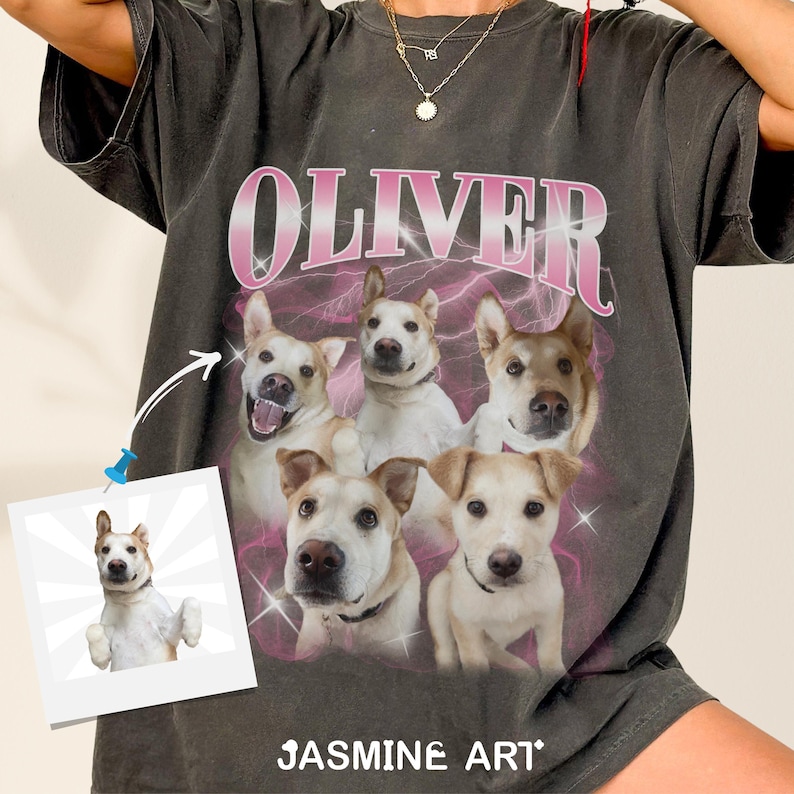 Op de afbeelding: Een zwart T-shirt met een roze afbeelding van het woord "OLIVER" en vijf honden. De honden zijn in een cirkel rond het woord gerangschikt. Het T-shirt heeft ook de tekst "JASMINE ART" onderaan.