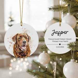May include: Two white, round Christmas ornaments. One features a watercolor portrait of a brown dog. The other ornament has the name "Jasper" and the text "Forever loved. Forever missed. Forever in our hearts." with a date.