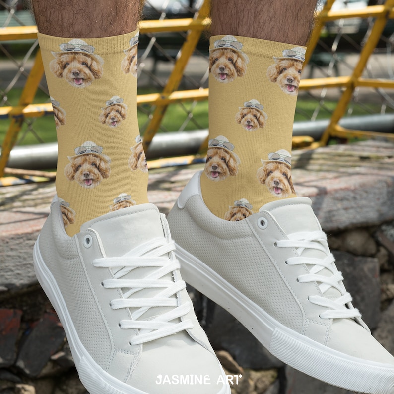 May include: A pair of white sneakers with a yellow and brown patterned socks featuring a dog wearing a hat. The socks are crew socks and the sneakers are low-top.