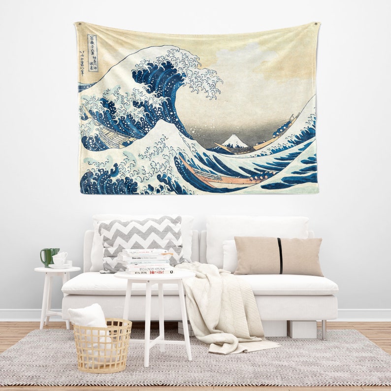 May include: A tapestry featuring a large blue wave crashing over a boat with Mount Fuji in the background. The wave is depicted in a traditional Japanese style with white foam and blue water. The background is a light yellow with a hint of pink.