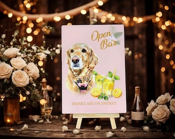 Op de afbeelding: Een roze bord op een houten ezel met de tekst "Open Bar" en "Drinks are on Smokey". Het bord toont een portret van een golden retriever, met illustraties van cocktails en citroenen. De achtergrond bevat bloemen en feeërieke lichtjes.