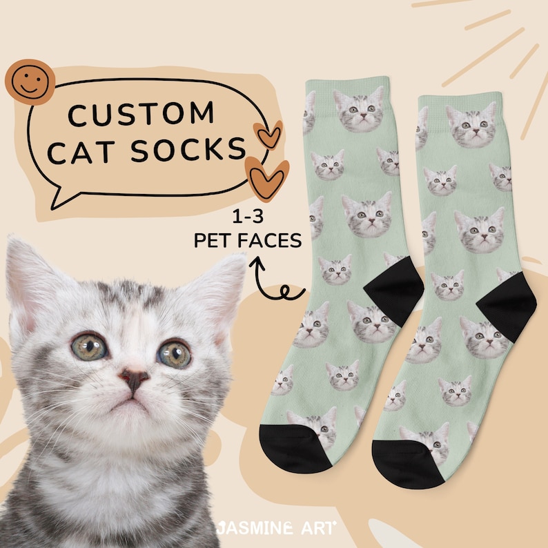 May include: A pair of custom cat socks with a light green background and a repeating pattern of a cat's face. The socks are black at the toes and heels. The text "CUSTOM CAT SOCKS" is in a speech bubble above the socks. The text "1-3 PET FACES" is in a speech bubble with an arrow pointing to the socks.