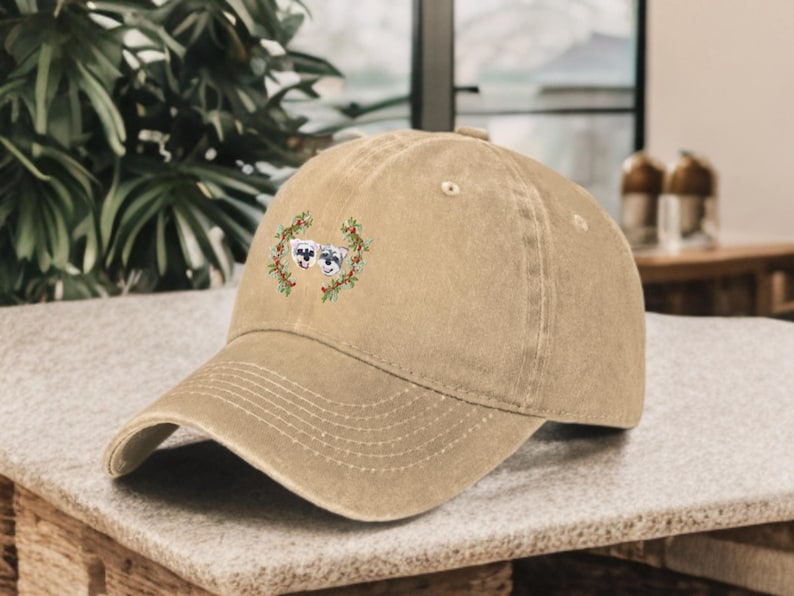 May include: A tan baseball cap with an embroidered design of two dogs wearing a wreath of green leaves.