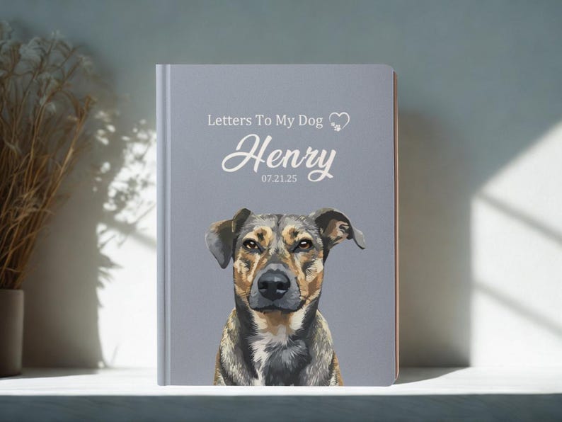 Pode incluir: Um di&aacute;rio personalizado com um retrato de c&atilde;o na capa. A capa cinza apresenta o texto "Letters To My Dog" e o nome do c&atilde;o, "Henry", com uma data abaixo. O c&atilde;o &eacute; castanho, preto e castanho claro.