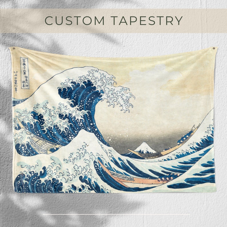 May include: A tapestry featuring a large blue wave crashing over a smaller wave, with Mount Fuji in the background. The wave is depicted in a traditional Japanese style, with white foam and a blue-grey color. The tapestry is made of a soft, woven fabric and has a vintage look.