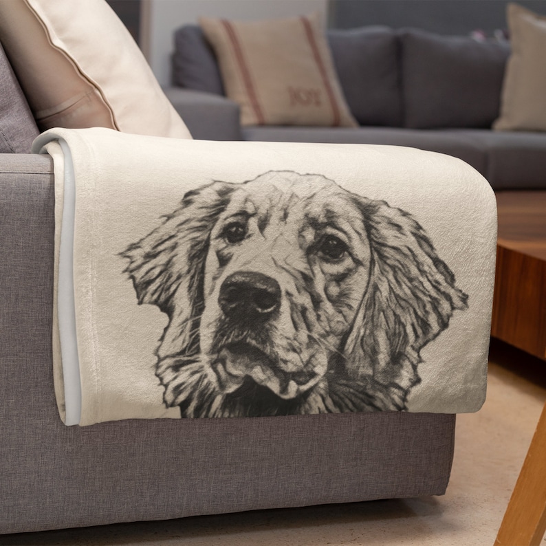 May include: A soft, cream-coloured fleece throw blanket with a black and white sketch of a golden retriever dog's head.