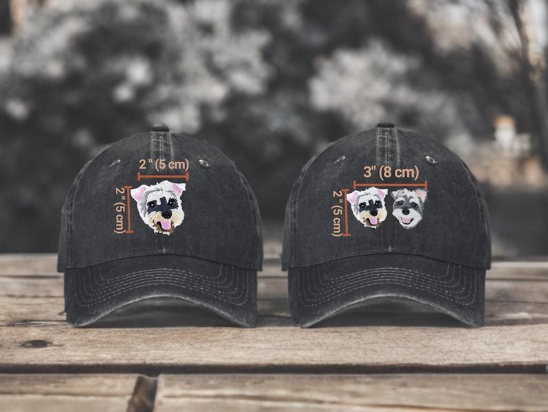 May include: Two black baseball caps featuring embroidered Schnauzer dog portraits. The left cap shows a single dog head measuring 2 inches by 2 inches. The right cap displays two dog heads measuring 3 inches wide by 2 inches high.