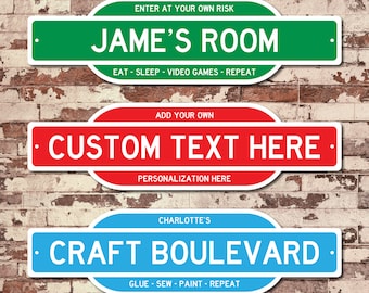 May include: Three custom street sign style door signs with rounded edges. The top sign is green with white text that reads "ENTER AT YOUR OWN RISK JAME'S ROOM EAT - SLEEP - VIDEO GAMES - REPEAT". The middle sign is red with white text that reads "ADD YOUR OWN CUSTOM TEXT HERE PERSONALIZATION HERE". The bottom sign is blue with white text that reads "CHARLOTTE'S CRAFT BOULEVARD GLUE - SEW - PAINT - REPEAT".
