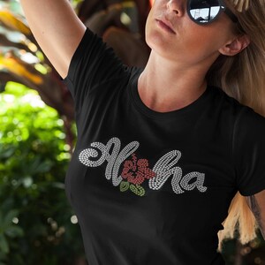 May include: Black t-shirt with a white rhinestone design that says "Aloha" with a red hibiscus flower in the middle.
