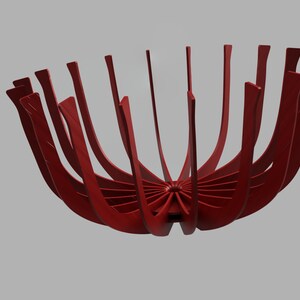 May include: A red metal bowl with a unique design. The bowl is made of many thin, curved pieces of metal that are joined together at the center. The bowl is open at the top and has a wide, shallow base.