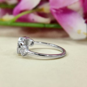 May include: A silver ring featuring a large oval-shaped gemstone and two smaller square-shaped gemstones. The ring is displayed against a white backdrop.