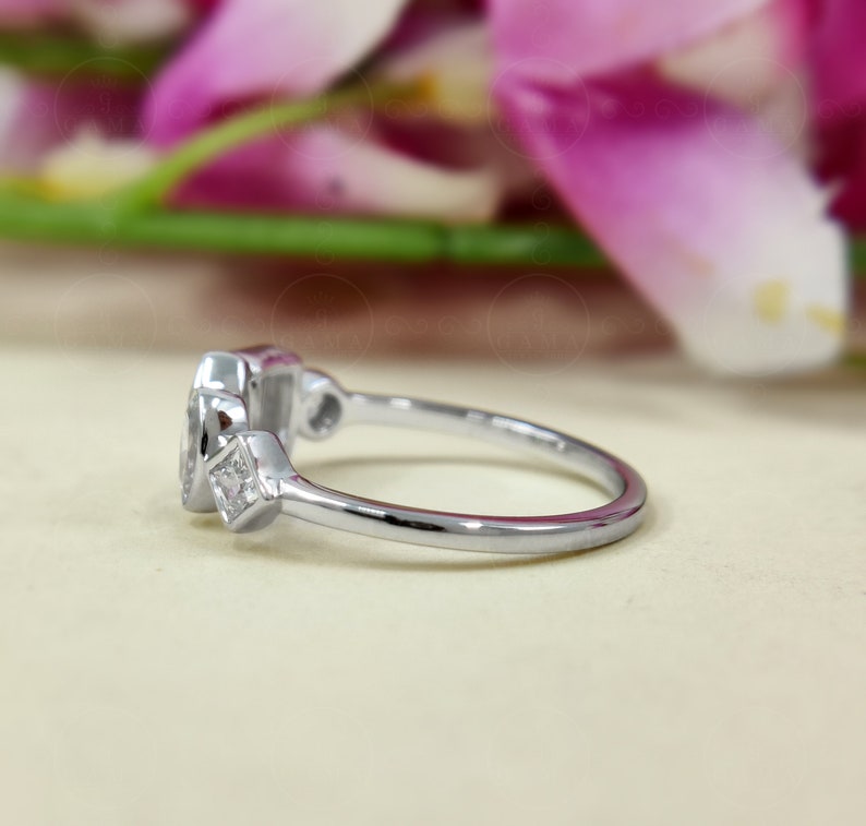 May include: A silver ring featuring a large oval-shaped gemstone and two smaller square-shaped gemstones. The ring is displayed against a white backdrop.